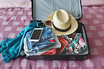 Close-up of various objects in luggage on bed