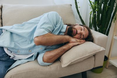 Low section of woman sitting on sofa at home