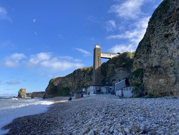 Lighthouse by sea against sky