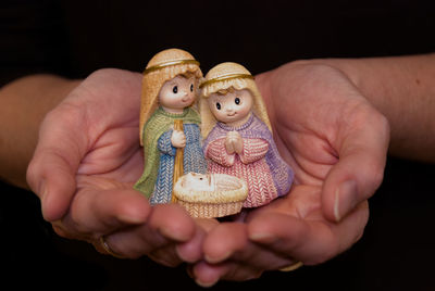 Close-up of hand holding toys against black background