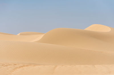 Sand dunes in desert against clear sky