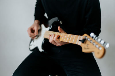 Midsection of man playing electric guitar