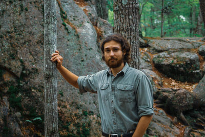 Portrait of young man standing in forest