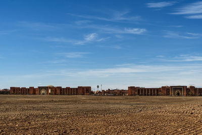 Buildings on field against blue sky