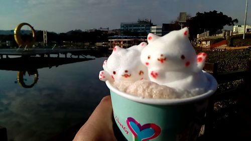 Close-up of hand holding ice cream against sky