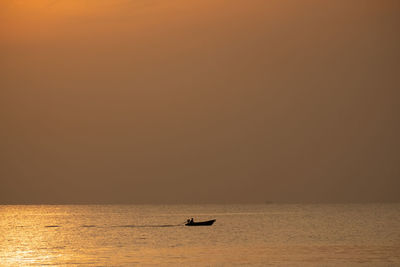 Silhouette boat in sea against sky during sunset
