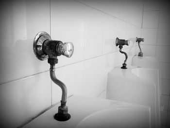 Close-up of urinals on tiled wall