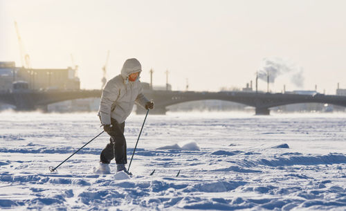 Woman skier riding on ice of the frozen neva river at sunny day, winter in st.petersburg