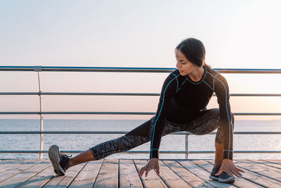 Young woman looking at railing against clear sky