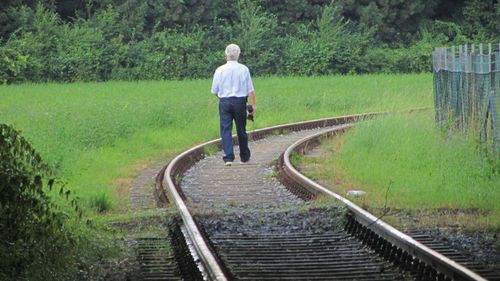 Rear view of man standing on railroad track