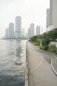 City buildings by road against sky