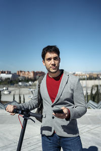 Portrait of young man standing against clear blue sky