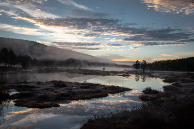 Picturesque natural landscape panorama in norway with mist rising above water and cloudscape