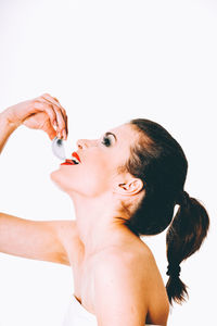 Portrait of a beautiful young woman drinking water against white background