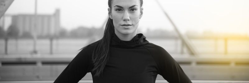 Portrait of young woman standing against blurred background