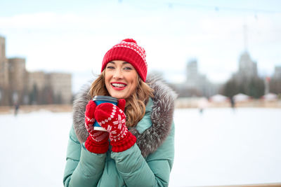 Portrait of smiling young woman wearing knit hat standing outdoors