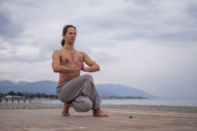 Man doing yoga under cloudy sky