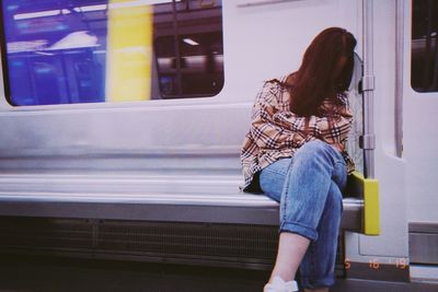 Rear view of woman standing against train window