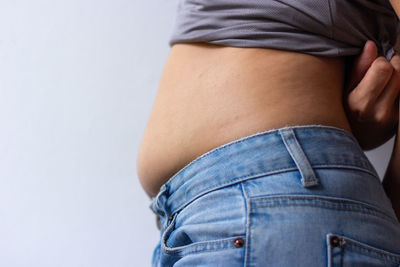 Midsection of woman standing against white background