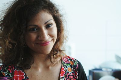 Close-up of young woman smiling while standing against wall