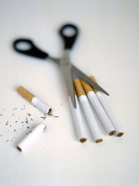 High angle view of cigarettes and scissor on table