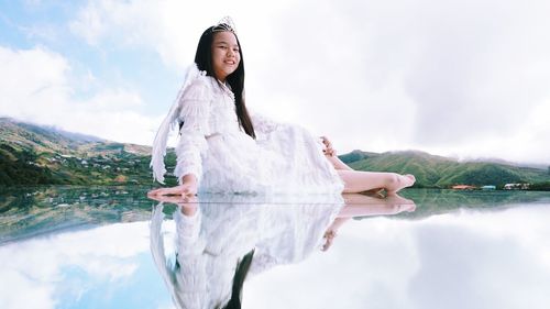 Woman standing by lake against sky