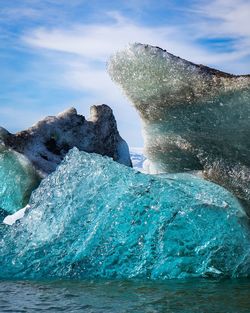 Close-up of iceberg on sea against sky