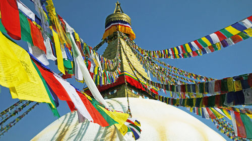 Low angle view of multi colored flags in building against sky in kathmandu, boudhanath stupa