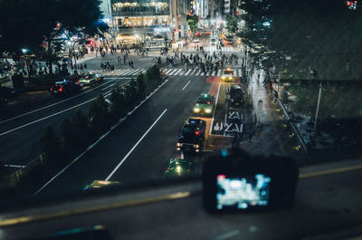 High angle view of street in illuminated city seen through window at night