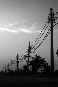 Low angle view of electricity pylon on field against sky