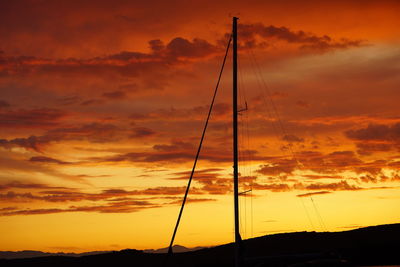 Silhouette of sailboat against cloudy sky during sunset