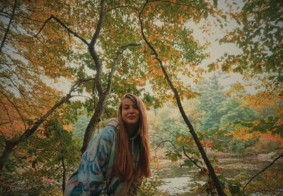 Portrait of smiling woman standing by plants during autumn