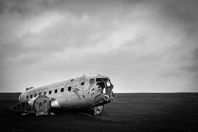 Abandoned airplane on beach against sky