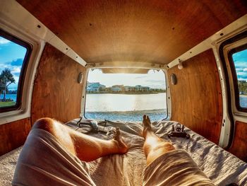 Low section of person relaxing by window in bus