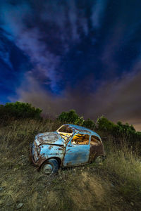 Abandoned car on field against sky