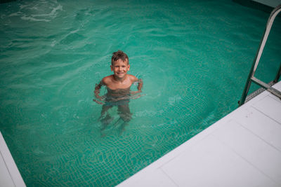 High angle view of shirtless boy in swimming pool