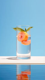 Glass of clean water for drinking with ice and peach on stand against the backdrop of the sea