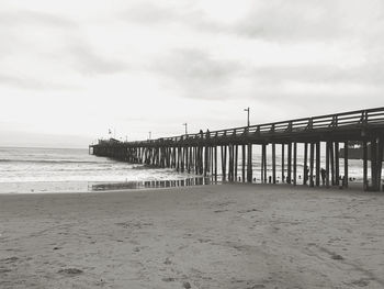 Pier on beach against sky