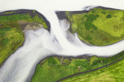 Drone view of rough rocky brown formations surrounded by lush green plants covered with thick fog in nature of iceland