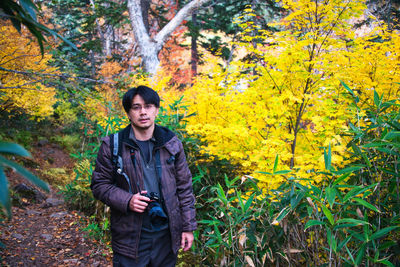 Portrait of young man standing in forest