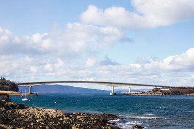 Bridge over sea against cloudy sky