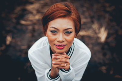 High angle portrait of young woman with hands clasped standing on field