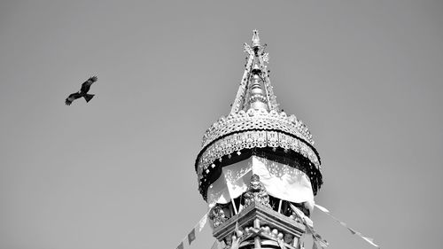 Low angle view of temple building and eagle against clear sky