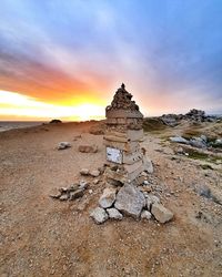 Stone wall on land against sky during sunset