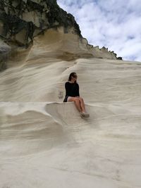 Low angle view of woman sitting on rock formation