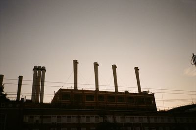 Low angle view of factory against sky during sunset
