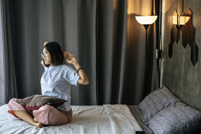 Woman sitting on bed at home