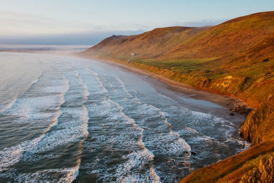 Scenic view of sea by mountains against sky