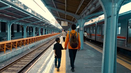 Rear view of woman walking on railroad station