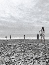 People playing on beach against sky